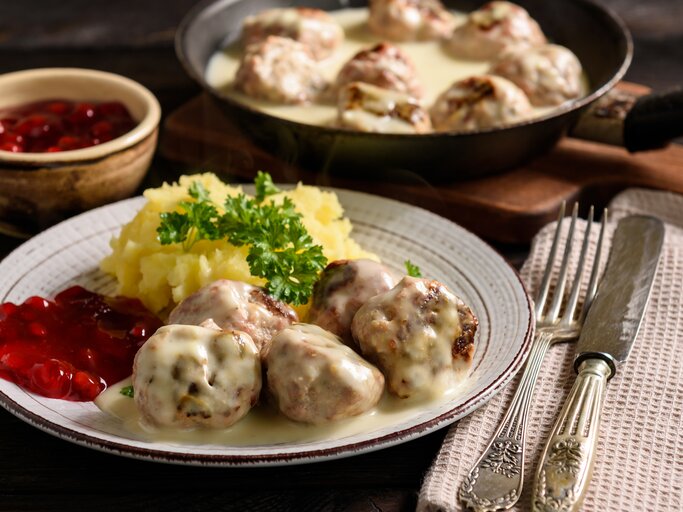 Rustikaler Teller mit Kartoffeln, Preiselbeersoße, Hackbällchen "Köttbullar" und cremiger Soße.  | © iStock/iko636