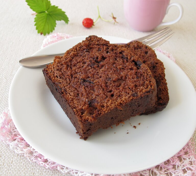 Zwei angeschnittene Stücke Schokoladenkuchen liegen auf einem weißen Teller. Daneben eine rosafarbene Tasse und ein Minzblatt.  | © iStock.com/HeikeRau