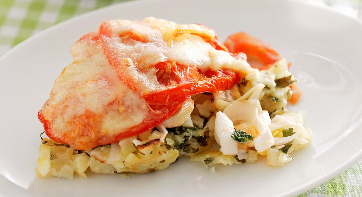 Eierlasagne auf einem weißen Teller. Das Ganze auf einer weiß-grün karierten Tischdecke