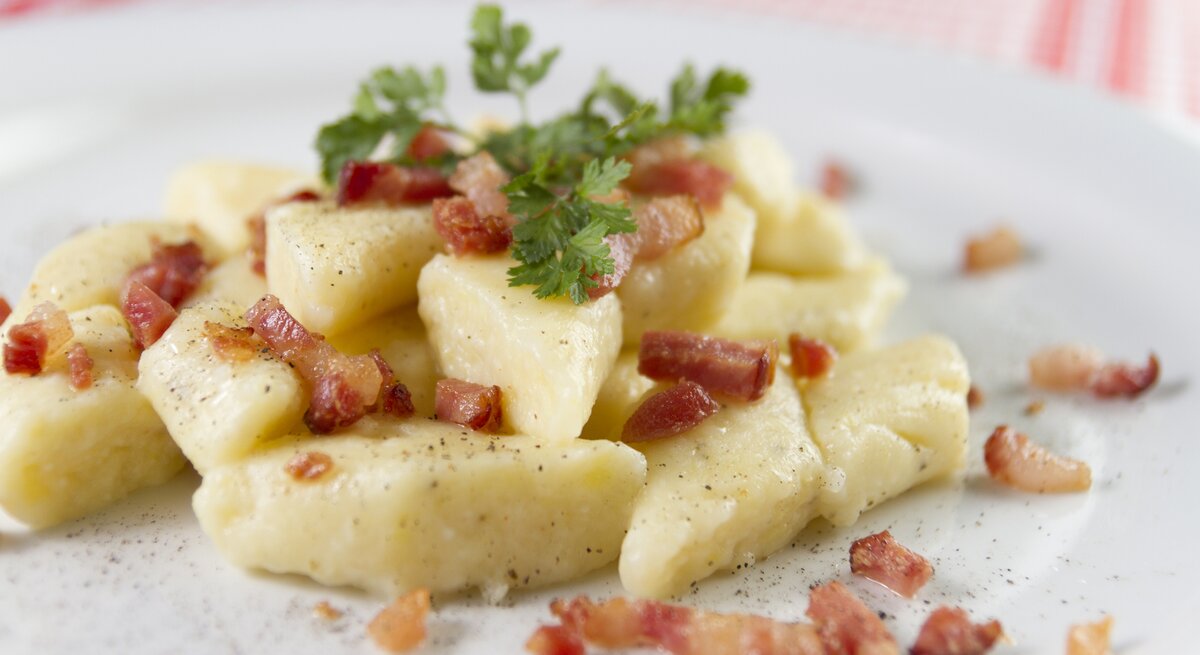 Polnische Klöße mit gebratenem Speck auf Teller. 