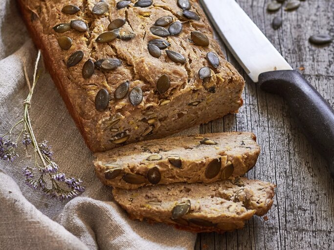 Ein angeschnittenes Zucchinibrot mit Banane. Daneben liegt ein großes Küchenmesser. | © StockFood / Krol, Helena