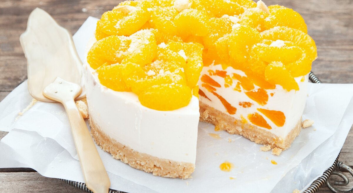 Weiße Sahnetorte mit Mandarinenstücken garniert.