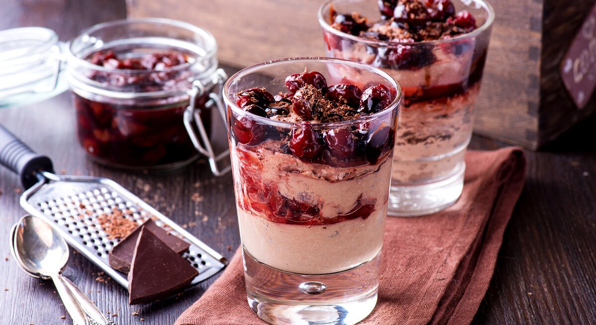Zwei Gläser gefüllt mit einem weihnachtlichen Dessert: Glühweinkirschen in einer zimtigen Mascarpone-Creme. 