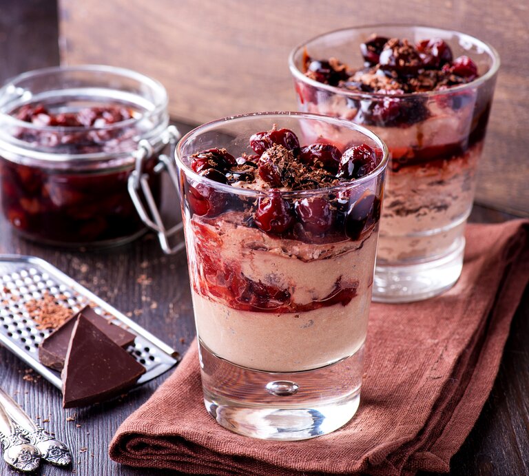 Zwei Gläser gefüllt mit einem weihnachtlichen Dessert: Glühweinkirschen in einer zimtigen Mascarpone-Creme.  | © iStock / etitarenko