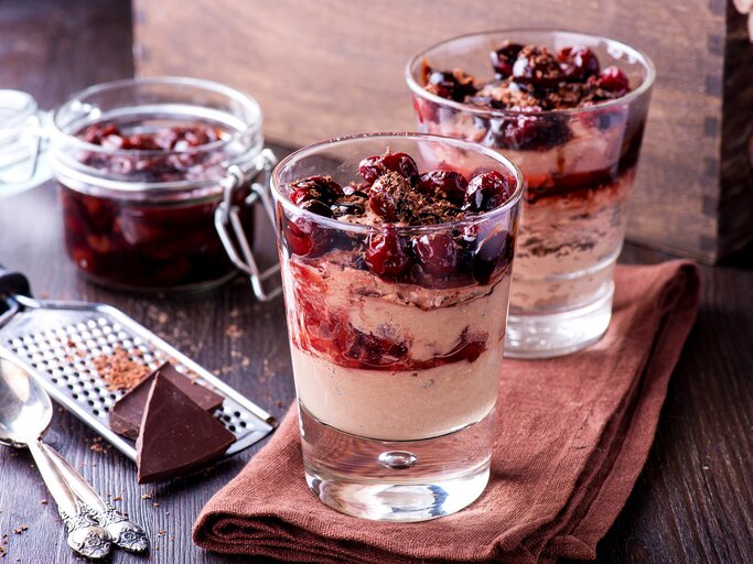Zwei Gläser gefüllt mit einem weihnachtlichen Dessert: Glühweinkirschen in einer zimtigen Mascarpone-Creme.  | © iStock / etitarenko