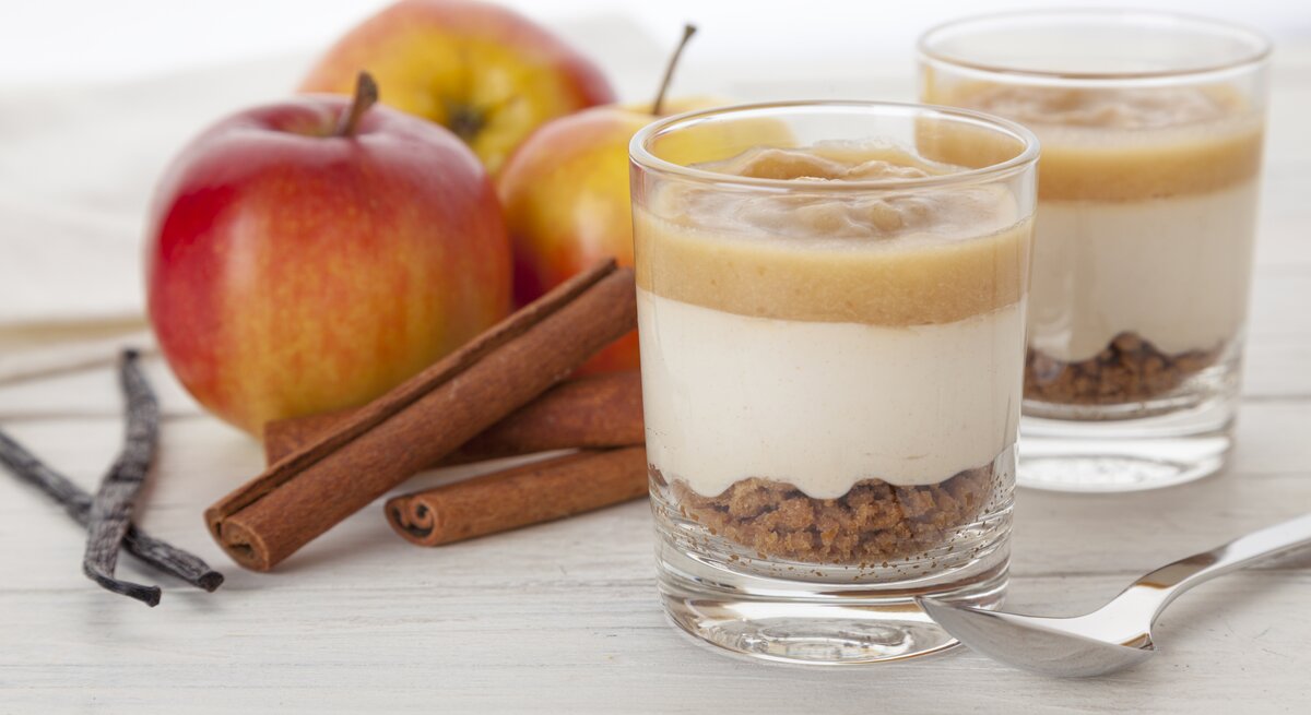zwei Gläser gefüllt mit einer Mischung aus Creme, Apfel und Kekskrümel.