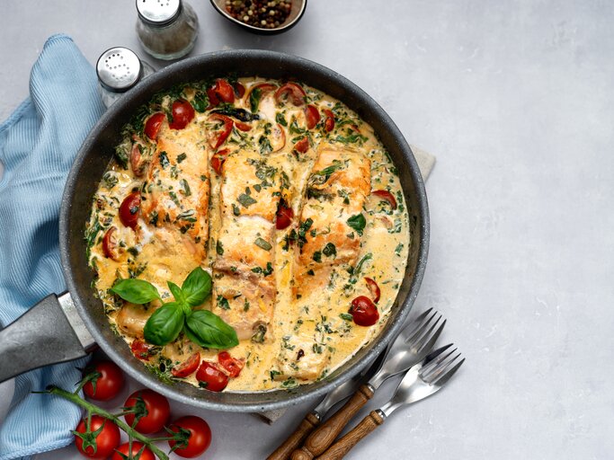 Draufsicht auf eine mediterrane Lachspfanne mit Tomaten & Spinat serviert in einer Pfanne.  | © iStock/Yummy pic