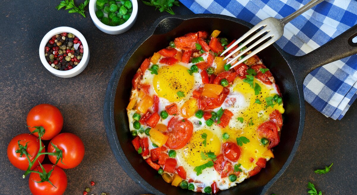 Draufsicht auf eine Eier-Tomaten-Pfanne garniert mit frischen Kräutern.