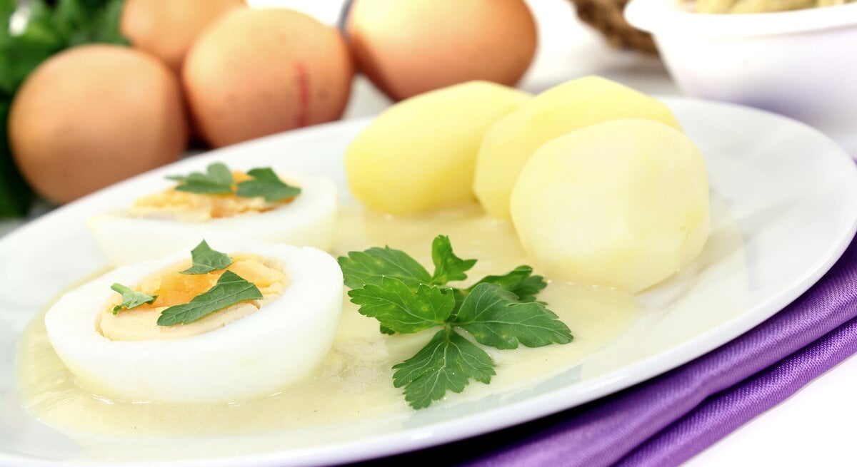 Senfeier auf weißem Teller, daneben Kartoffeln. 