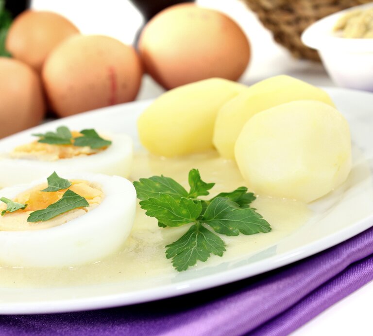 Senfeier auf weißem Teller, daneben Kartoffeln.  | © iStock / MarenWischnewski