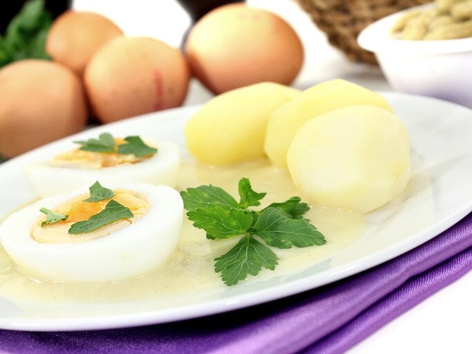 Senfeier auf weißem Teller, daneben Kartoffeln.  | © iStock / MarenWischnewski