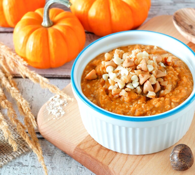 Eine weiß-blaue Schüssel mit Kürbis-Porridge auf einem Holzbrett. | © Shutterstock/Jenifoto