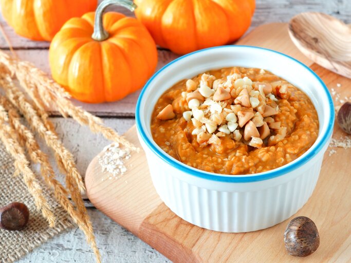Eine weiß-blaue Schüssel mit Kürbis-Porridge auf einem Holzbrett. | © Shutterstock/Jenifoto