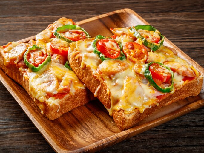 Überbackenes Toastbrot mit Tomaten und Würstchen auf Holzteller. | © Shutterstock/gontabunta