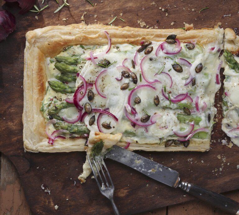 Ein dunkles Holzbrett mit der Tarte auf einem Holztisch direkt von oben fotografiert. | © Stockfood