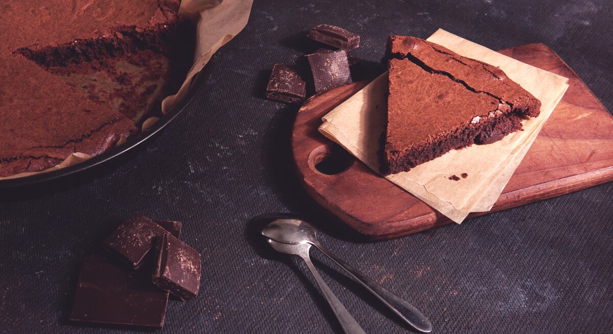Angeschnittener Schokokuchen auf dunklem Untergrund. 