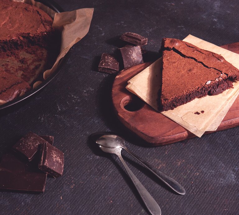 Angeschnittener Schokokuchen auf dunklem Untergrund.  | © iStock.com/YCbCr