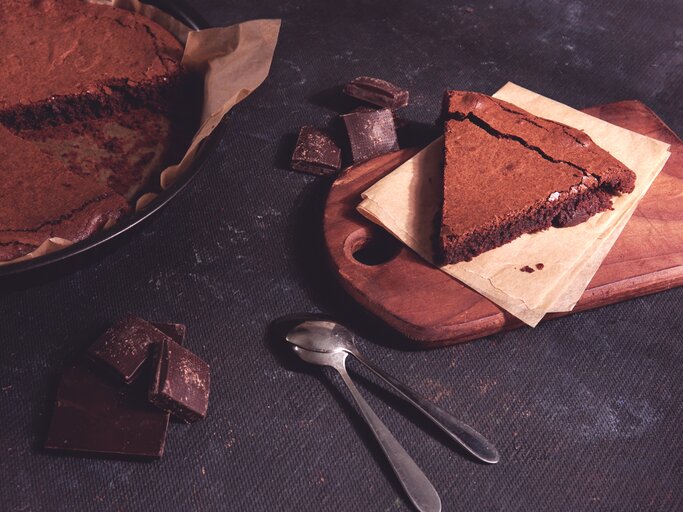 Angeschnittener Schokokuchen auf dunklem Untergrund.  | © iStock.com/YCbCr