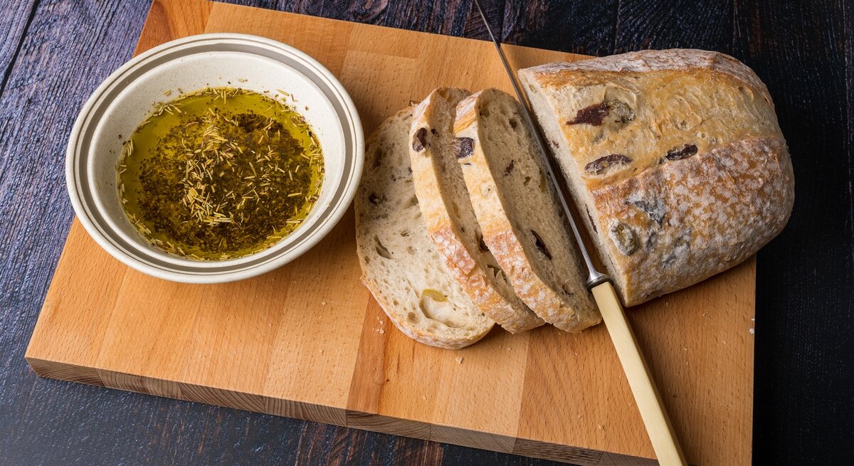 Ein Laib griechisches Olivenbrot auf einem Holzbrett.
