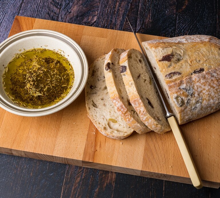Ein Laib griechisches Olivenbrot auf einem Holzbrett. | © Shutterstock/Christopher Willans