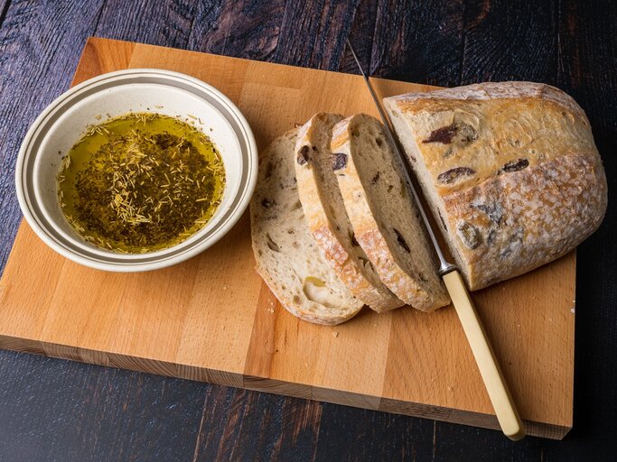 Ein Laib griechisches Olivenbrot auf einem Holzbrett. | © Shutterstock/Christopher Willans