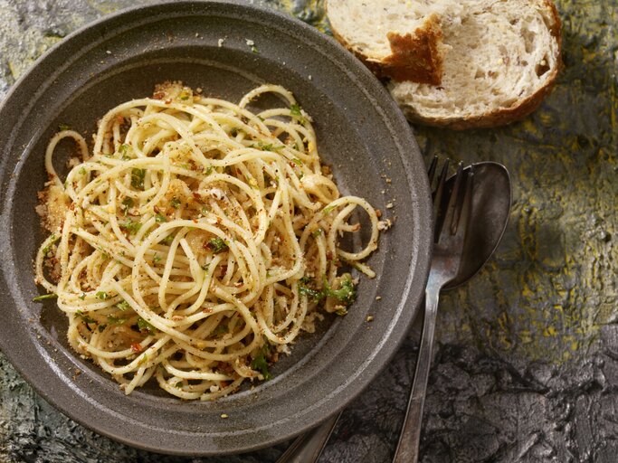 Draufsicht auf einen dunklen Teller befüllt mit Spaghetti Aglio, Olio e Peperoncini.  | © iStock / LauriPatterson