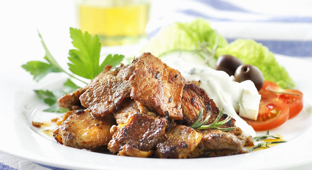 Weißer Teller, darauf angerichtet Gyros und Tzaziki.