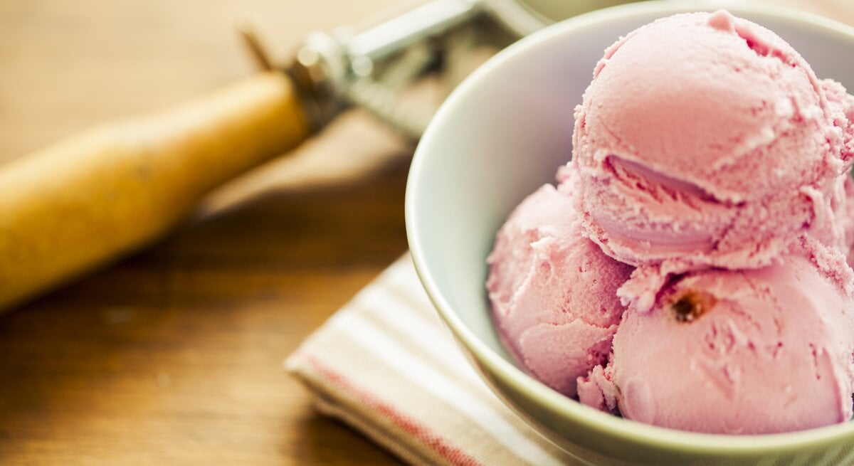 Mehrere Bällchen Erdbeer-Käsekuchen-Eis in einer weißen Schale. 