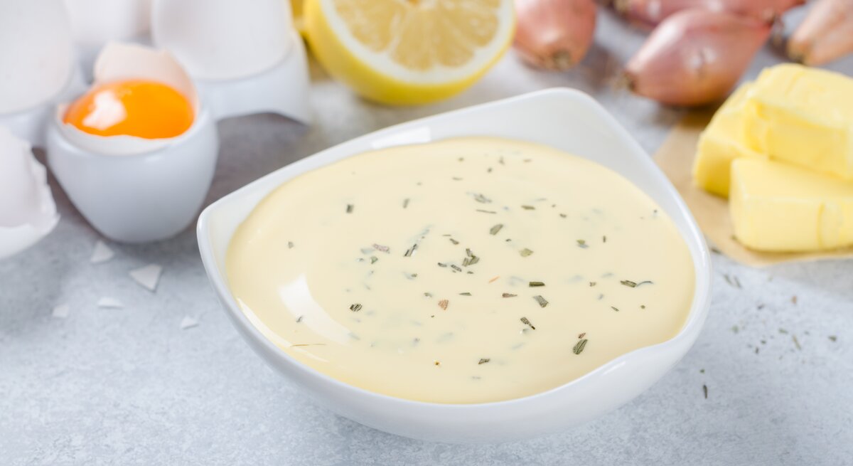 Sauce béarnaise in einer weißen Schale, daneben die klassischen Zutaten. 