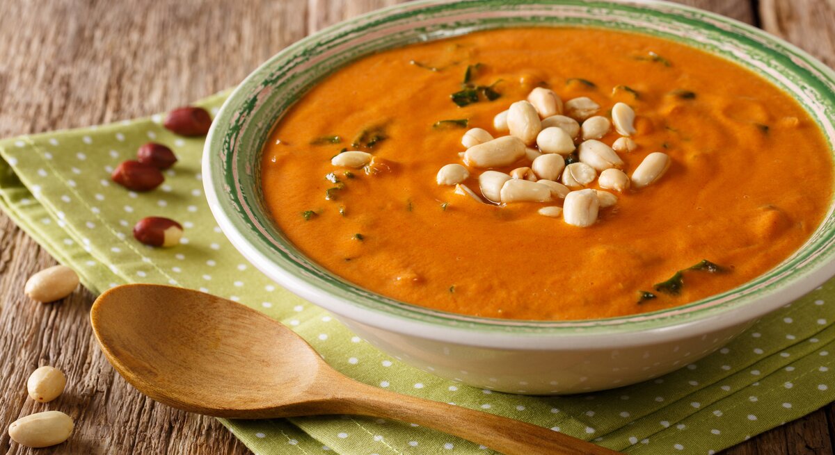 Seitliche Ansicht auf eine Schüssel afrikanische Erdnusssuppe auf Holztisch.