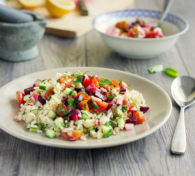 Ein Teller Reissalat mit Curry-Joghurt-Dressing auf einem Untergrund aus Holz / Frontalsicht | © iStock / haoliang