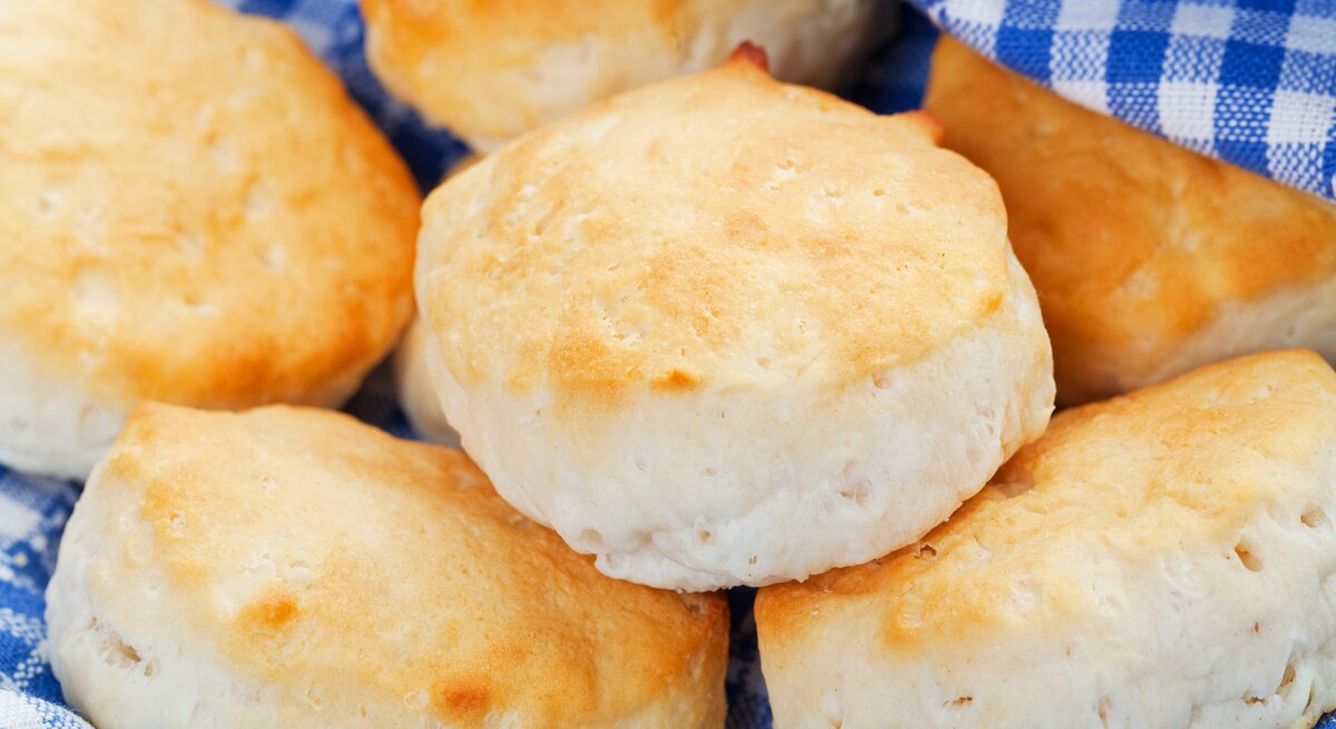 Einige Scones auf einem blau-weiß-karierten Tuch. Nah und von schräg oben fotografiert.