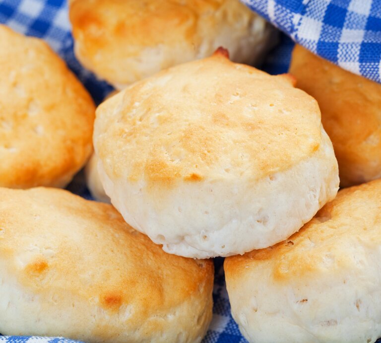 Einige Scones auf einem blau-weiß-karierten Tuch. Nah und von schräg oben fotografiert. | © iStock/Songbird839
