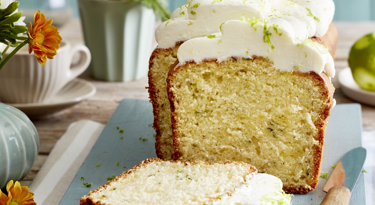 Angeschnittener Limetten-Zucchini-Kuchen auf einem blauen Teller. 