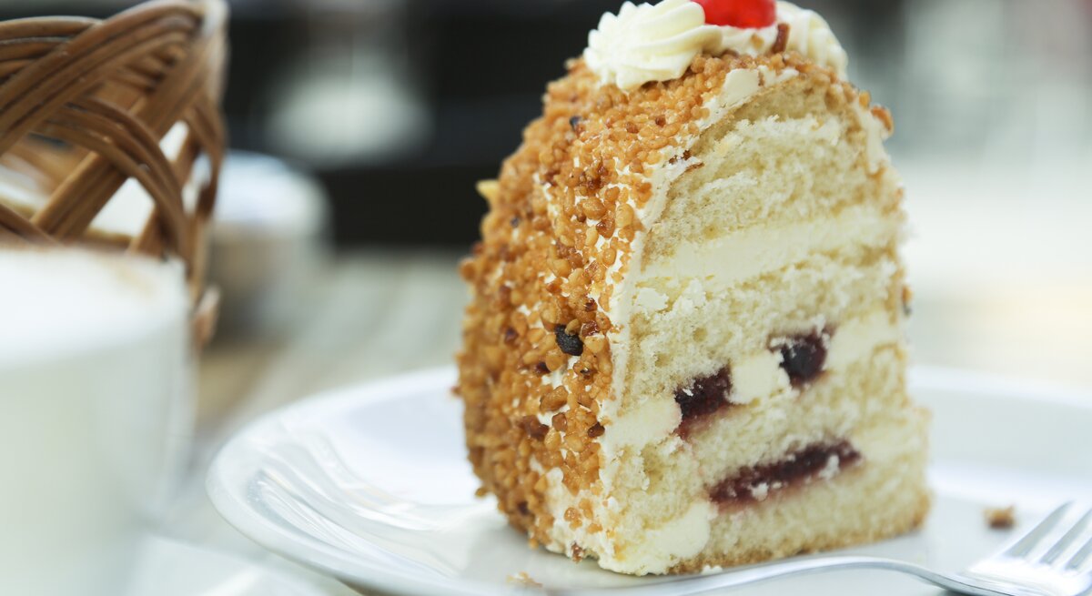 Ein Stück vom Frankfurter Kranz auf einem weißen Teller nah und von der Seite fotografiert.