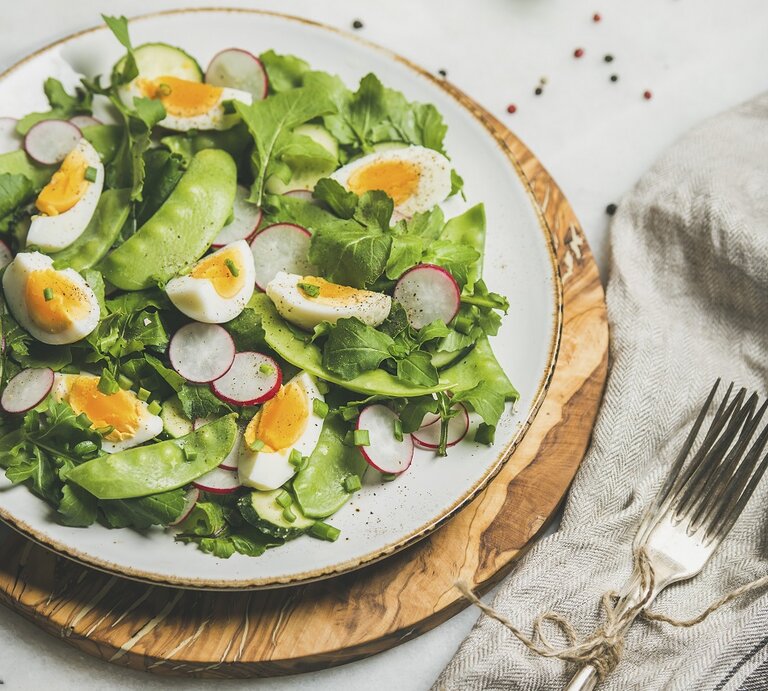 Rucolasalat mit Zuckerschoten, Radieschen und Ei / runder Teller / Holzbrett / Gabel / Nahaufnahme / Draufsicht | ©  StockFood / The Picture Pantry