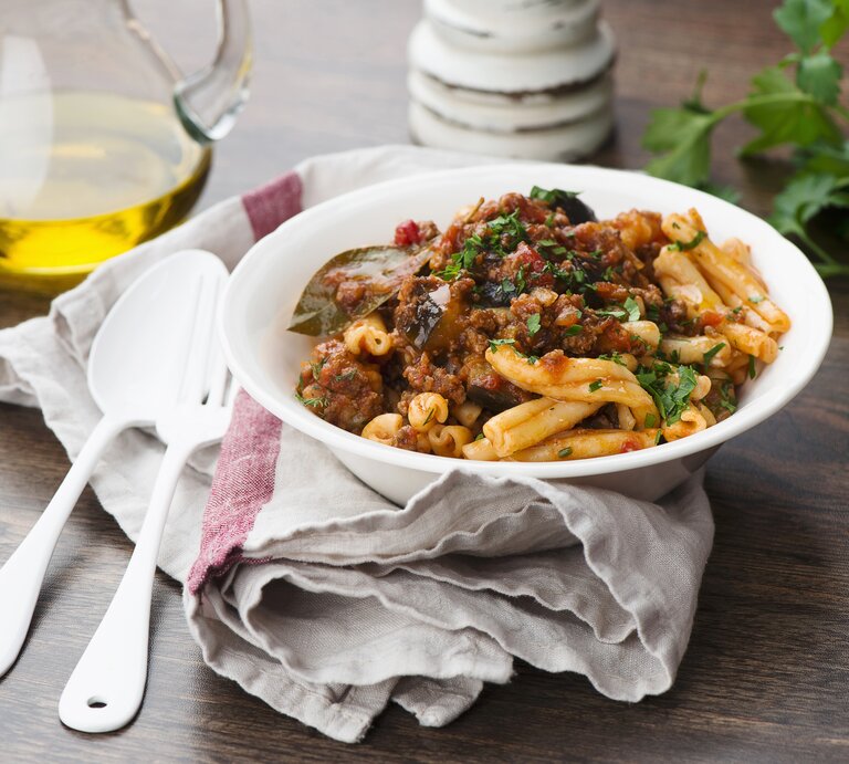 Ein weißer, tiefer Teller mit dem Pastagericht auf einem rustikalen Holztisch. | © StockFood/Schall, Ewgenija