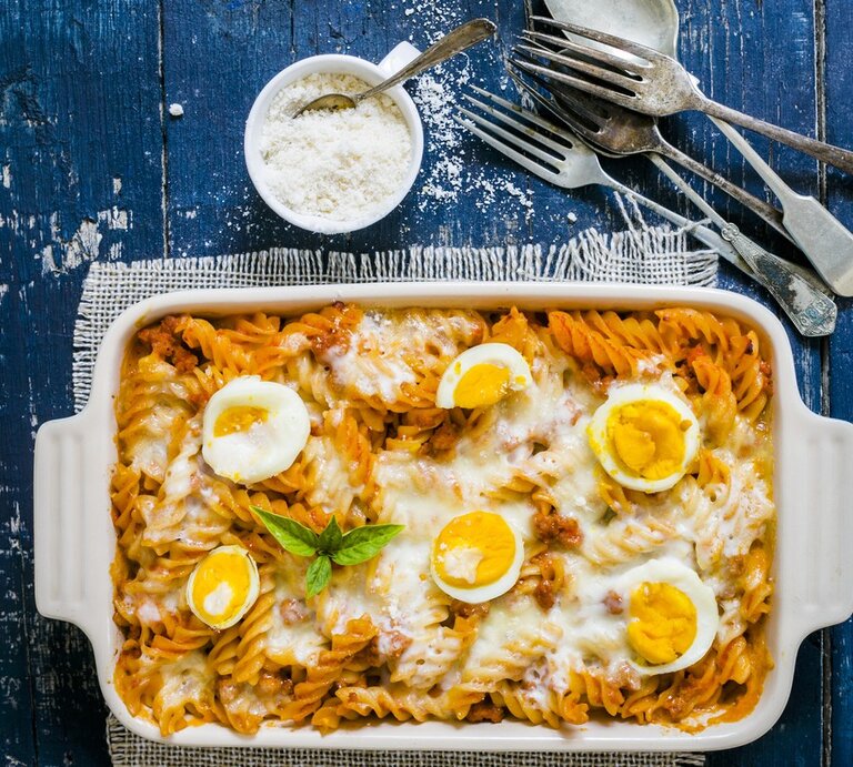 Weiße Form mit Nudelauflauf mit Eiern, daneben Besteck und Parmesan  | © Stock Food/  Avalos Flores, Maricruz
