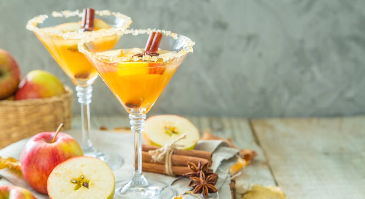 Zwei Martini-Gläser mit dem Getränk auf einem hellen Holztisch von vorne fotografiert.