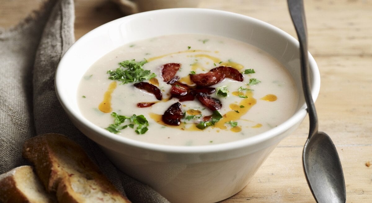 Draufsicht: Eine Schüssel mit einer Bohnensuppe, die mit Wurstscheiben zubereitet wird.
