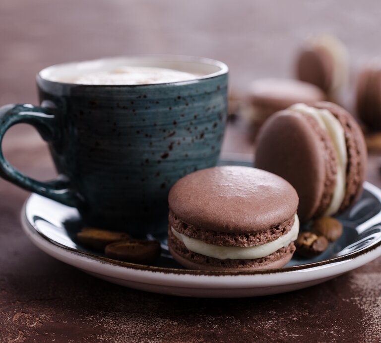 Süße Tiramisu-Kekse auf blauem Teller mit Kaffeetasse vor braunem Hintergrund | © Getty Images/ zia_shusha