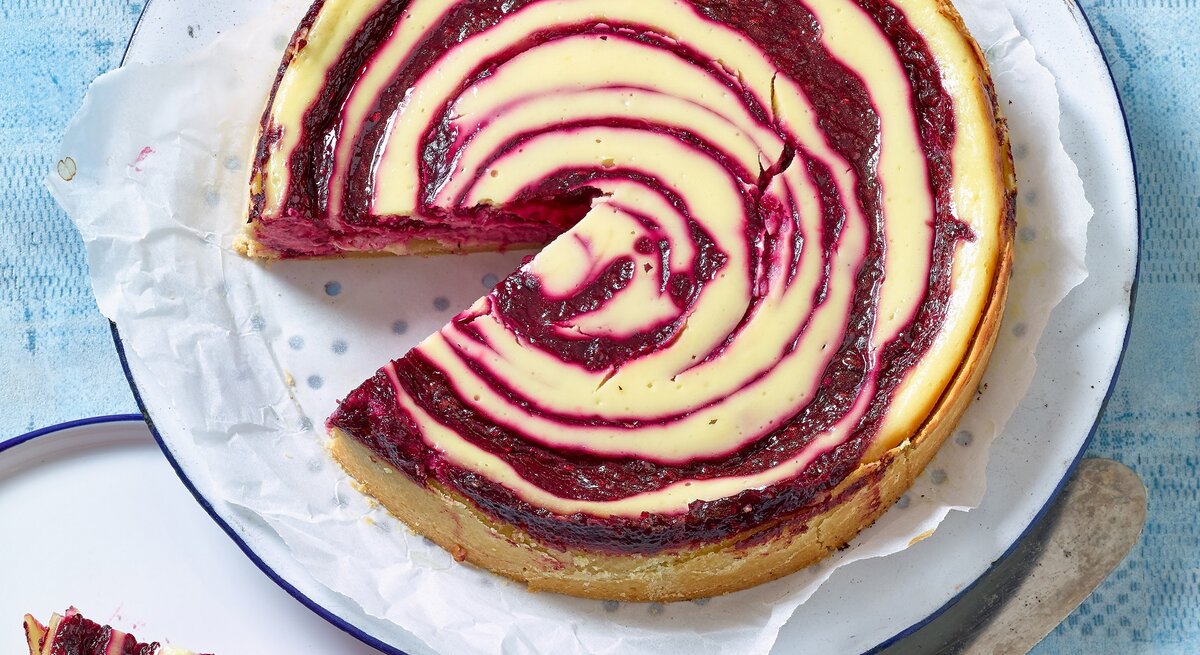 Käsekuchen mit Rote-Grütze-Quirl von oben fotografiert. 