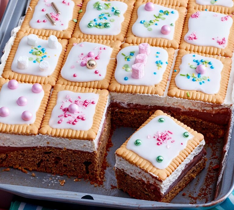 Blechkuchen mit Schokoladenboden, heller Creme und Butterkeksen mit weißem Zuckerguss und bunten Zuckerstreuseln, ein Stück ist herausgeschnitten. | © Eat Club/Isabell Triemer