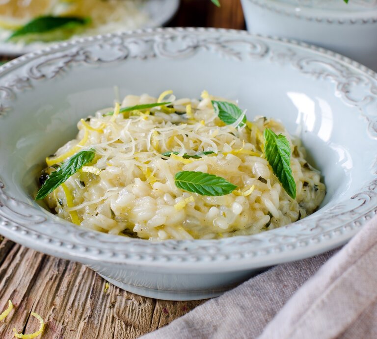 Ein tiefer Pasta-Teller mit Risotto mit Zitrone und Minze auf einem Holztisch. | © Shutterstock/teleginatania