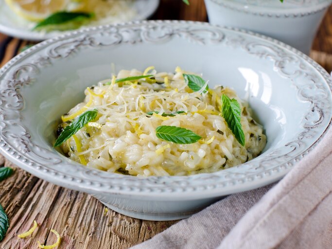 Ein tiefer Pasta-Teller mit Risotto mit Zitrone und Minze auf einem Holztisch. | © Shutterstock/teleginatania