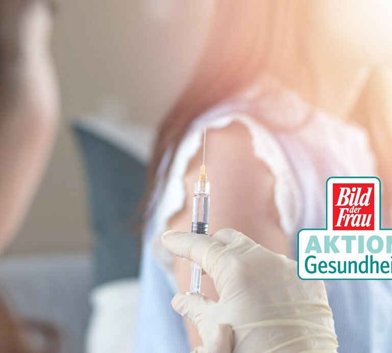 Im Vordergrund eine Spritze, dahinter verschwommen der Oberarm einer Frau. Daneben das Logo der "Aktion Gesundheit" von BILD der FRAU. | © iStock/Pornpak Khunatorn [M]