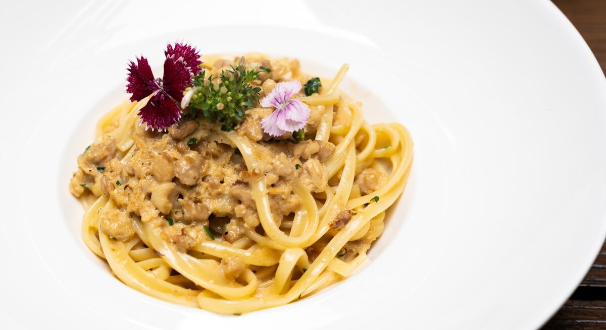 Weißer Teller mit Pasta und weißer Bolognese. 