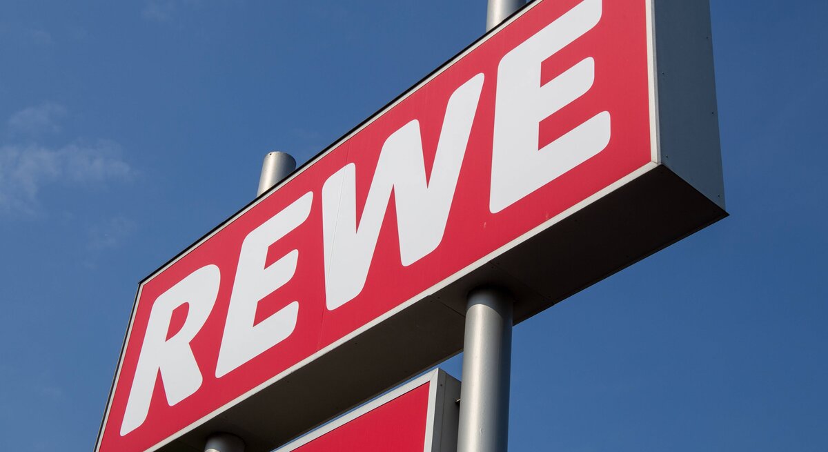 Das Rewe-Logo vor dem blauen Himmel