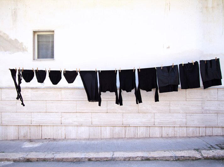 Schwarze Kleidung hängt an einer Leine in der Sonne | © iStock/JannHuizenga