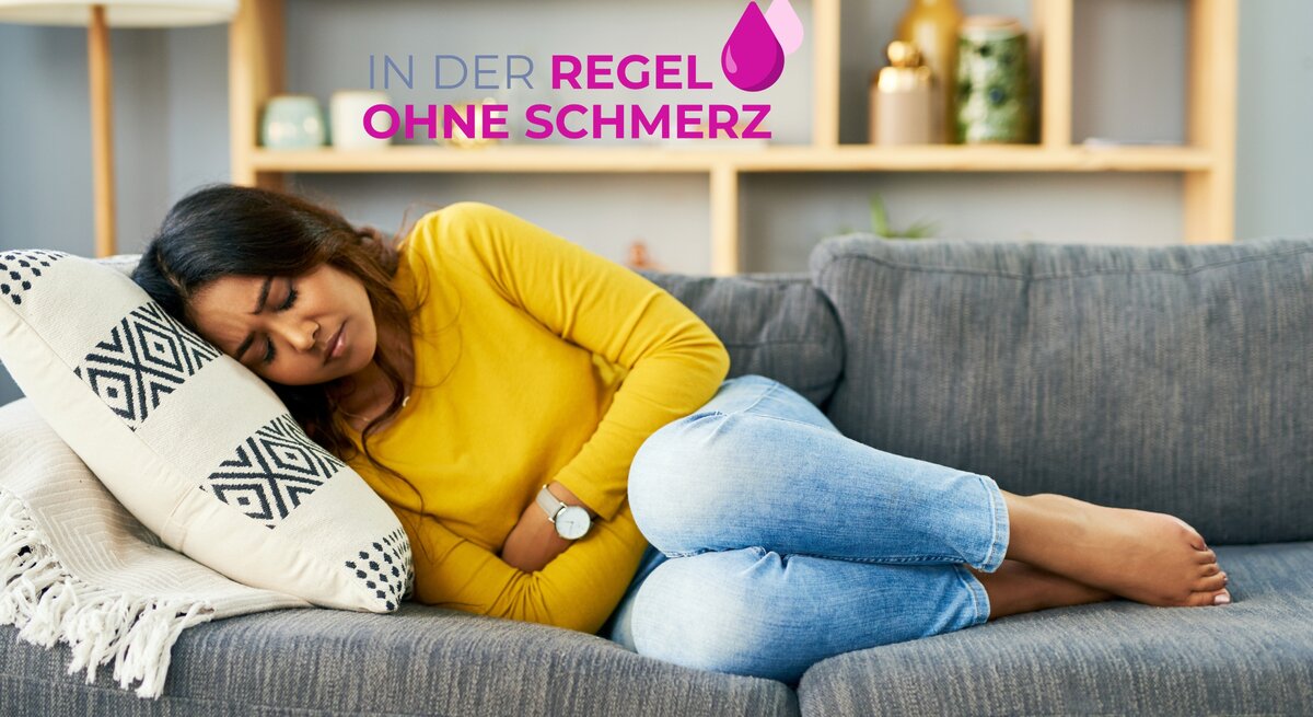 Eine junge Frau mit geschlossenen Augen liegt in fötaler Haltung auf einem grauen Sofa und umarmt ein dekoratives Kissen. Sie trägt ein leuchtend gelbes Oberteil und blaue Jeans. Ihr Gesichtsausdruck deutet auf Unwohlsein oder Schmerz hin. Über ihr schwebt der Text "IN DER REGEL OHNE SCHMERZ" in Großbuchstaben, begleitet von einem Tropfensymbol. Der Hintergrund des Bildes zeigt ein modernes Wohnzimmer mit einem Regal und Pflanzendekor, was eine häusliche und entspannte Atmosphäre vermittelt.